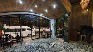 A lobby with patterned flooring, a reception desk, and a large window overlooking a street with parked cars. - Connector Hostel (Makati)