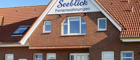 A brick building with a sign reading 'Seeblick Ferienwohnungen' and a telephone number.