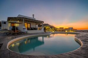 Une villa moderne dotée d’une piscine, d’un espace salon extérieur et offrant une vue sur les montagnes.