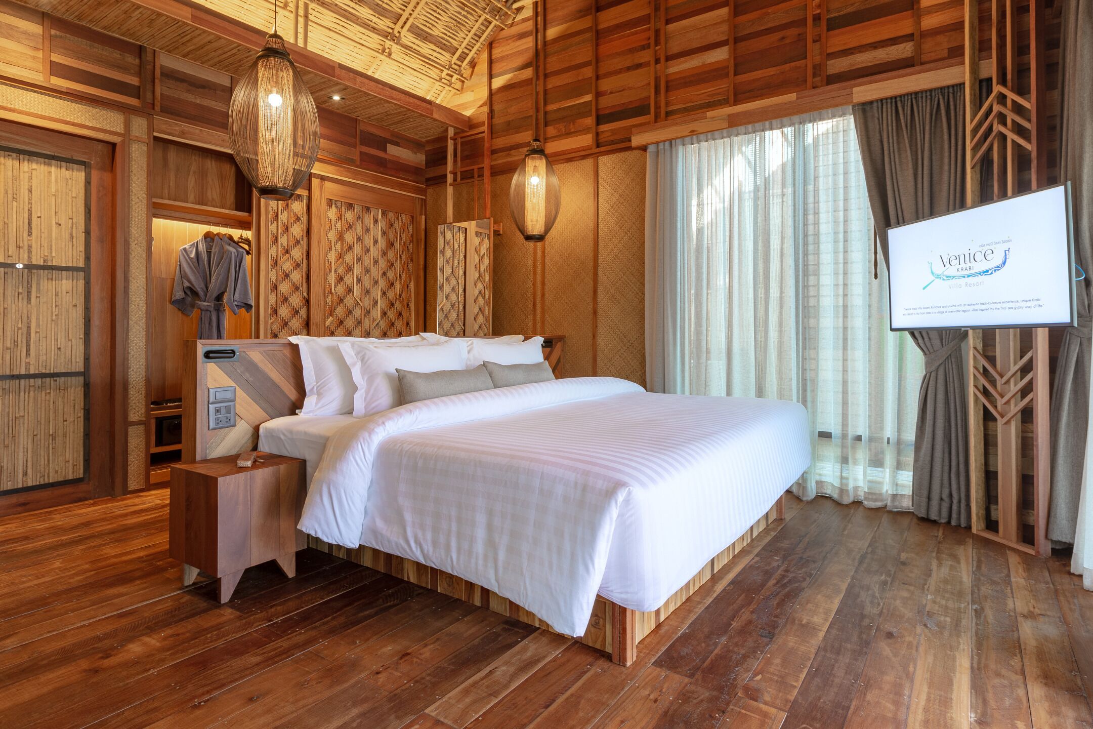 Een ruime slaapkamer met een groot bed, houten vloer, houten plafond en een televisiescherm dat 'Venetië' toont.