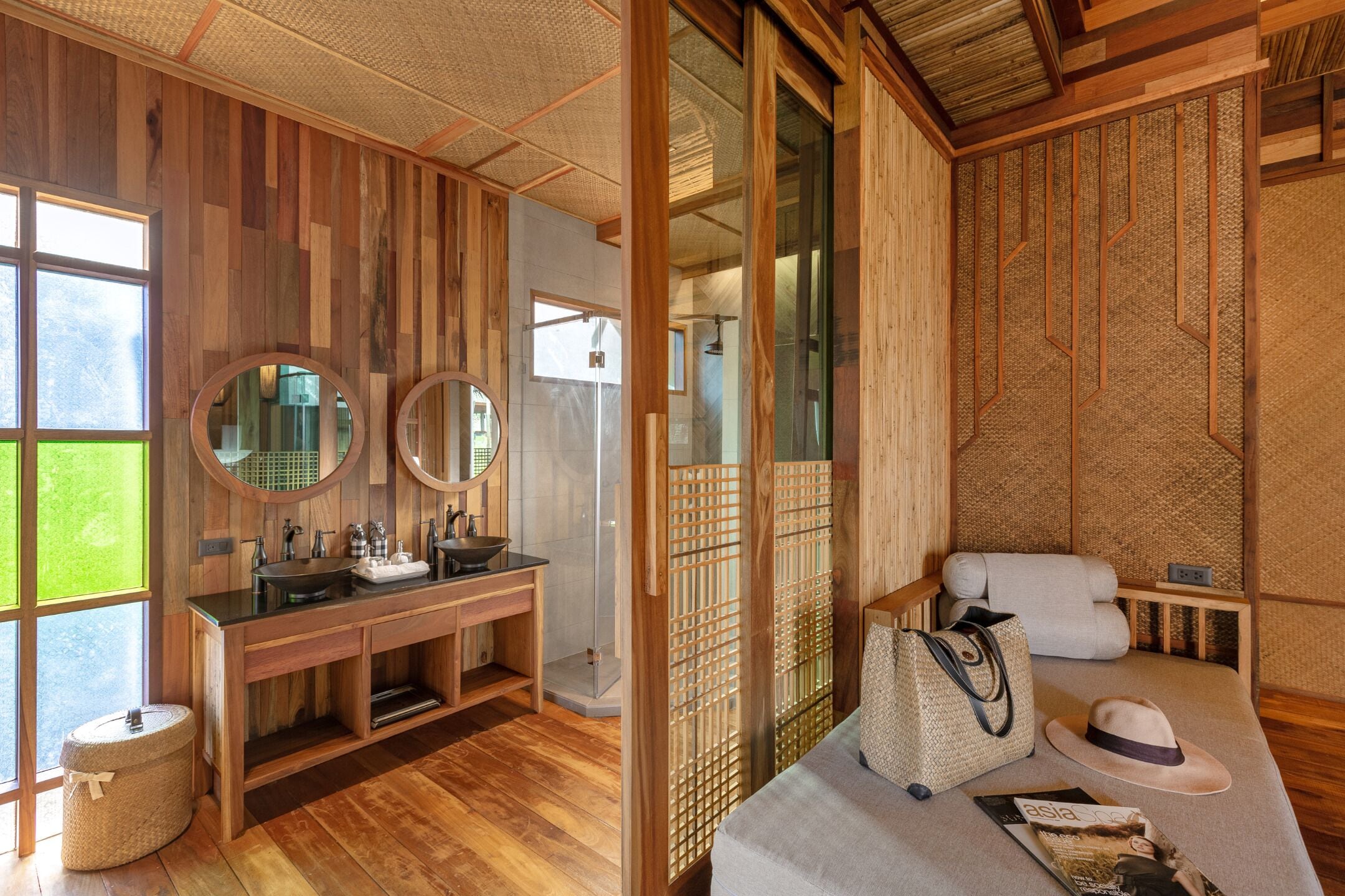 Interior de madera con tocador de madera, dos espejos, un lavabo y una cesta grande de fibra.