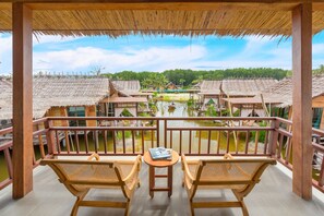 Un balcon doté de mobilier en bois, offrant une vue sur des maisons traditionnelles et un plan d’eau.
