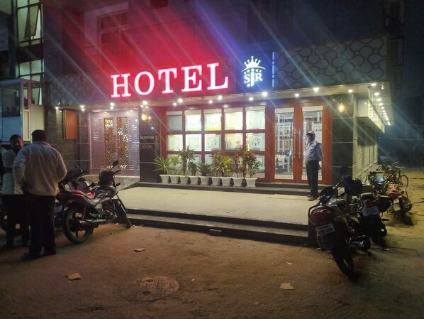 Um hotel com um letreiro grande 'HOTEL', entrada de vidro e várias motocicletas estacionadas na frente.