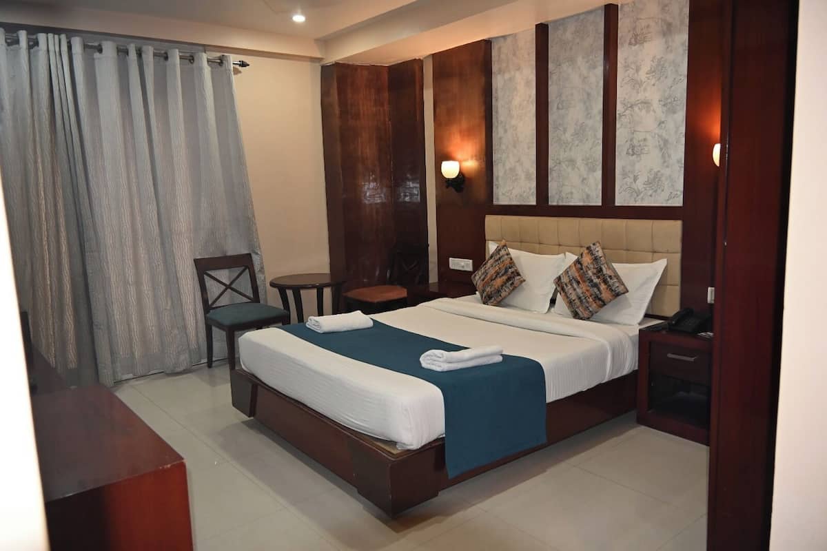A hotel room with a large bed, a desk, a chair, and a small table.