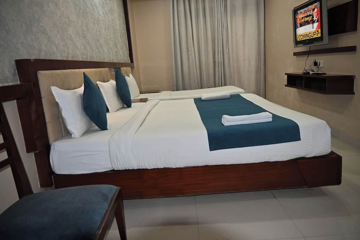 A hotel room with a large bed, a wooden headboard, and a television mounted on the wall.