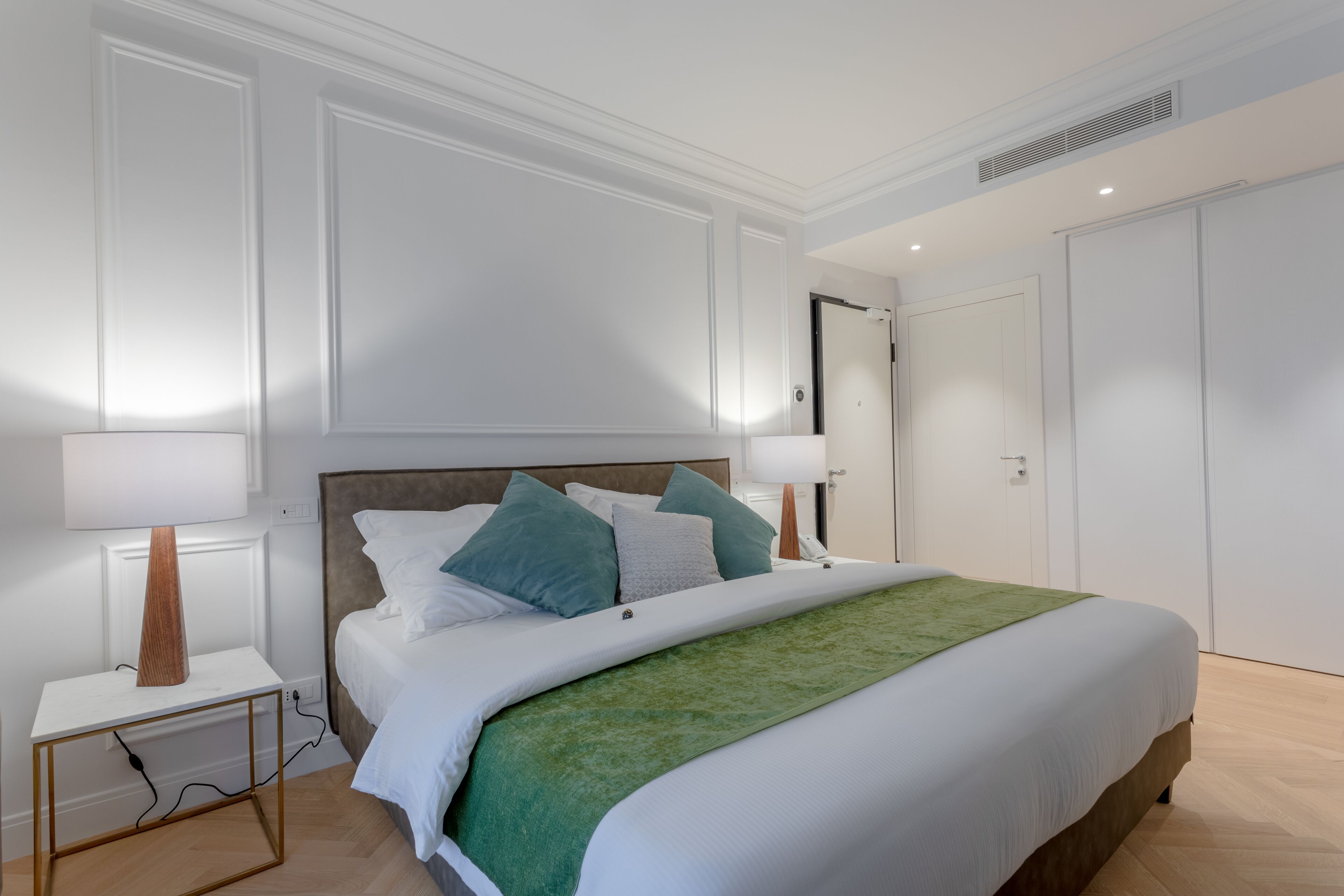 Une chambre à coucher moderne avec un grand lit, des murs blancs et une tête de lit en bois.