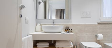 Un baño moderno con un lavamanos grande de color blanco, un inodoro y una zona de ducha.