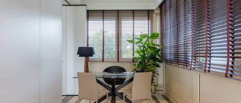Un comedor con una mesa de vidrio, dos sillas, una lámpara y una planta en maceta.