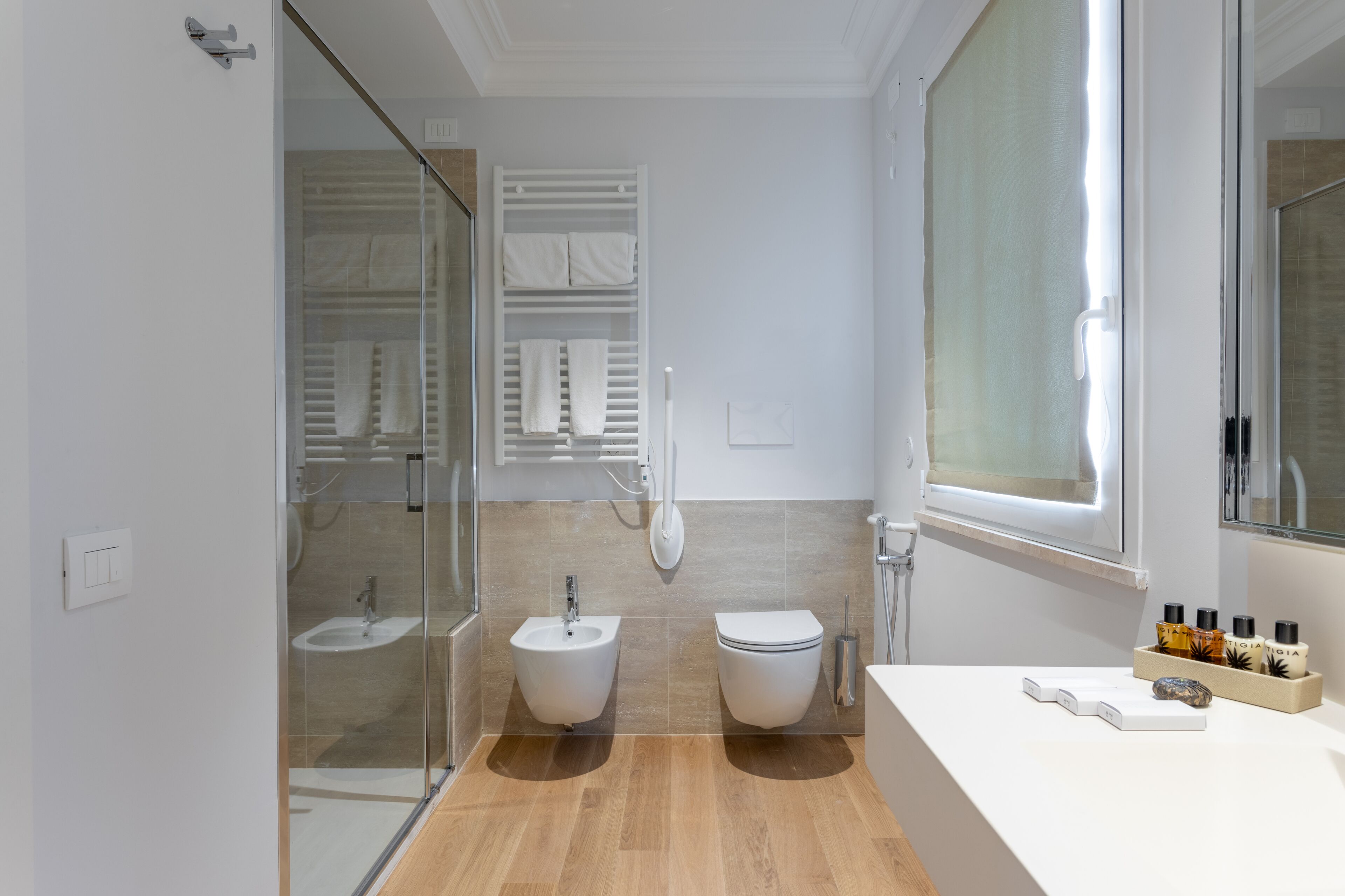 Un baño moderno con cabina de ducha de vidrio, un bidé, un inodoro y un tocador con artículos de aseo.