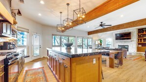 A spacious kitchen with a large island, wooden cabinetry, and a stone countertop. - Modern Fischer House w/ Deck, Fire Pit & Hot Tub! (Fischer)