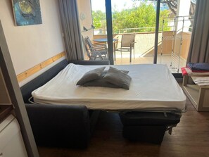A room with a bed, a small table, and a chair. There is a balcony with a railing and a view of greenery. - Côte d'Azur escape at Parcs de Grimaud (Grimaud)