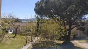 A residential area with a large tree, a building with a tiled roof, and a clear blue sky.