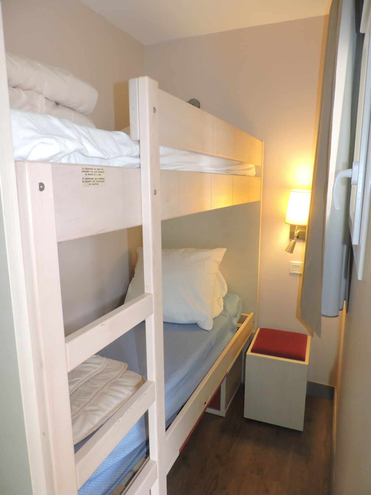 A bunk bed room with a small bedside table and a lamp.