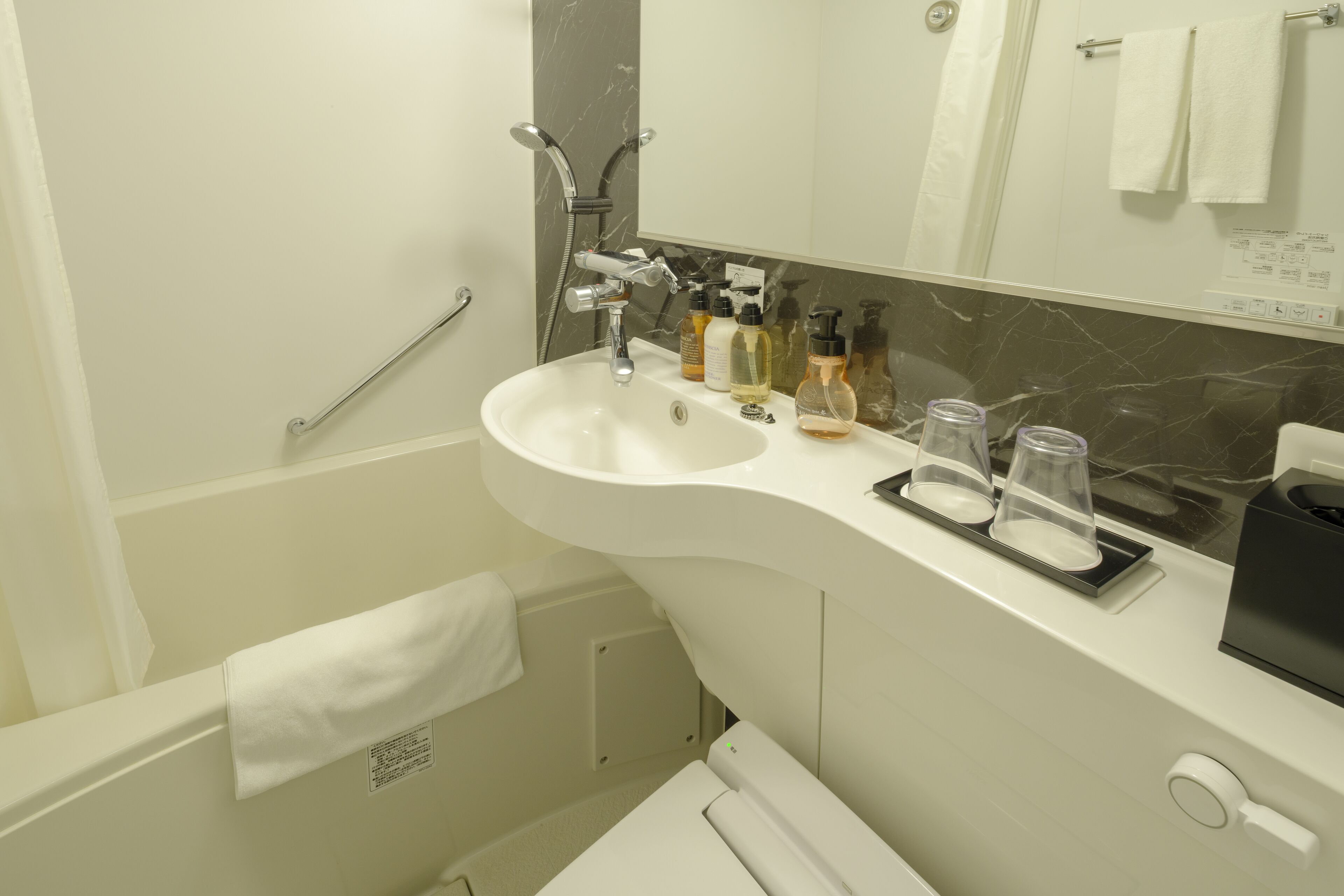 Une salle de bain moderne avec un lavabo blanc, un miroir et un espace douche.