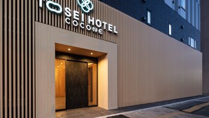 The exterior of the Tosei Hotel Cocowave, featuring a modern facade with vertical wooden slats and a prominent entrance. - Tosei Hotel Cocone Asakusa Kuramae (Tokyo)