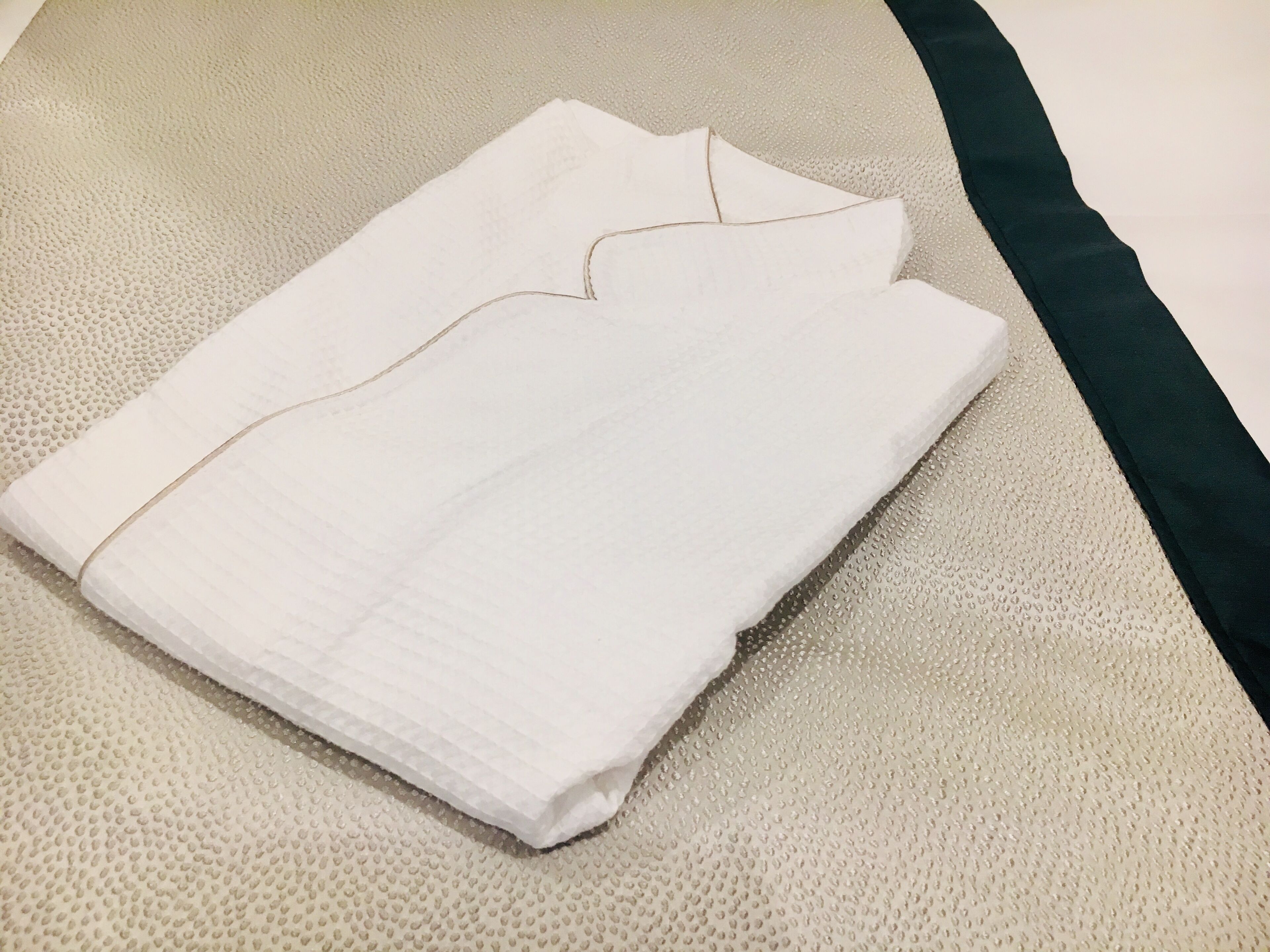 A neatly folded white garment on a textured beige surface.
