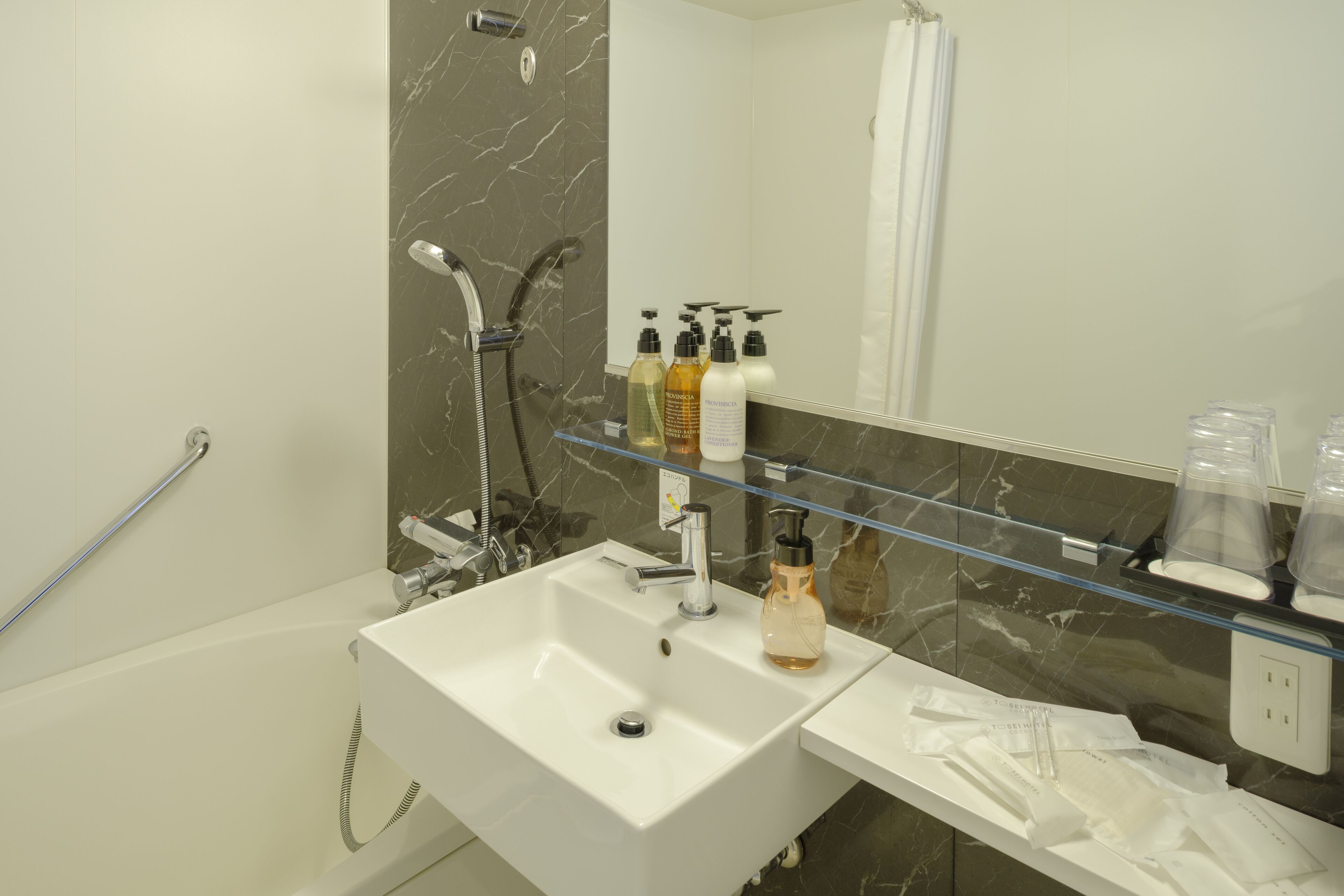 A modern bathroom with a white sink, a glass shower enclosure, and a marble backsplash.