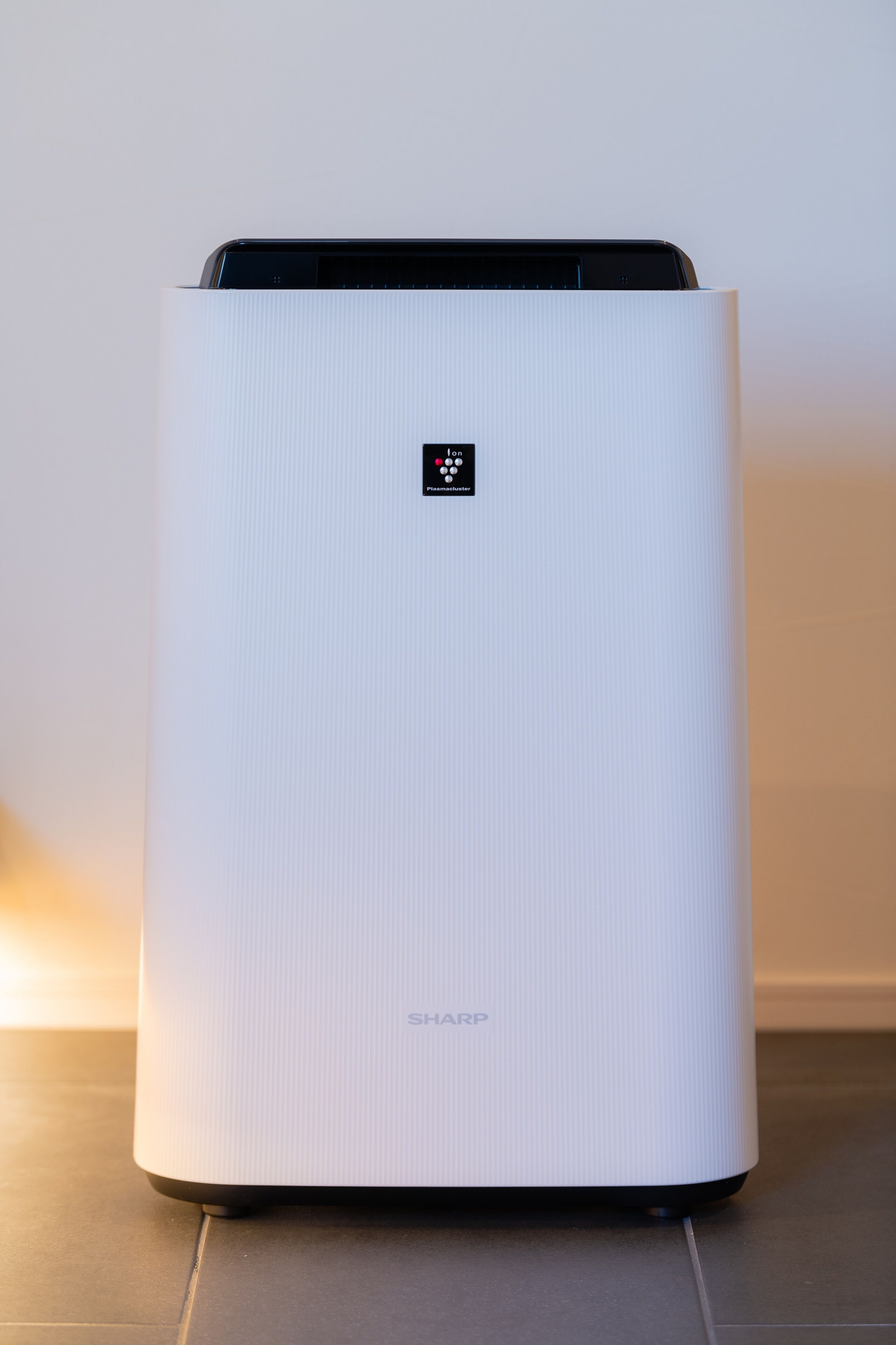 A white, rectangular air purifier with a digital display and the brand name "SHARP" visible on the front.
