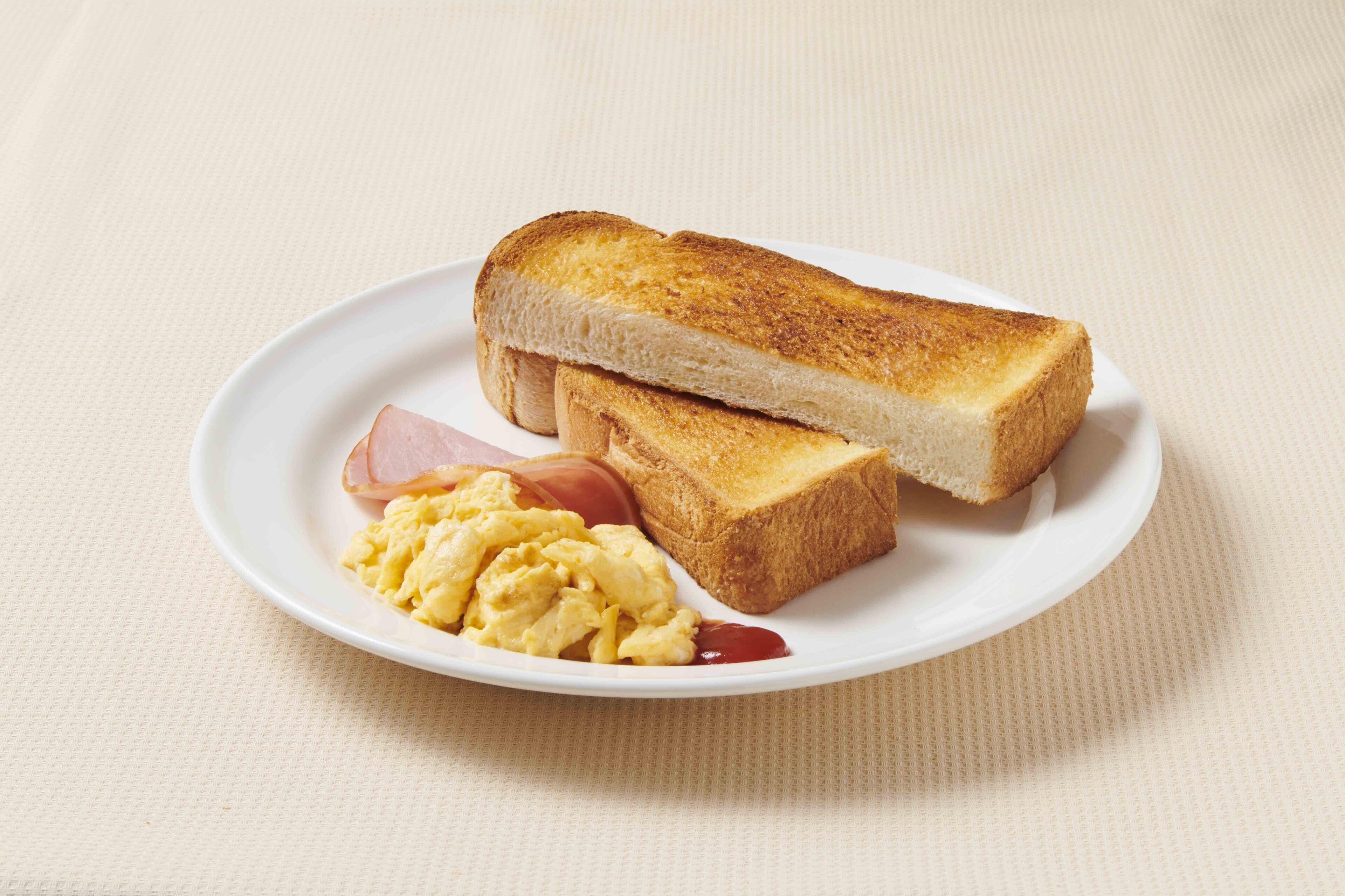 Une assiette avec des tranches de pain grillé, des œufs brouillés et une tranche de jambon.