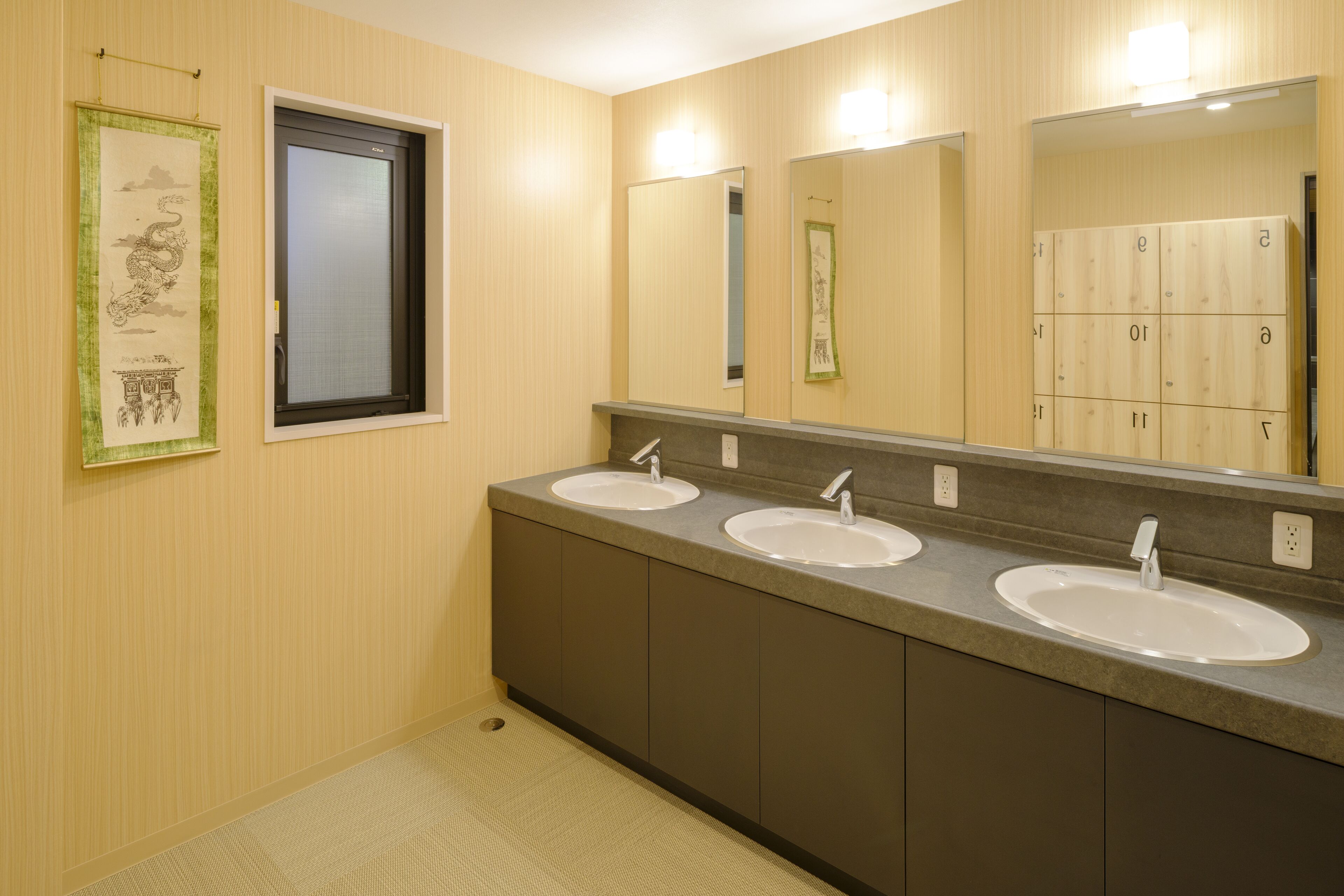 A bathroom with three sinks, a large mirror, and a towel rack.