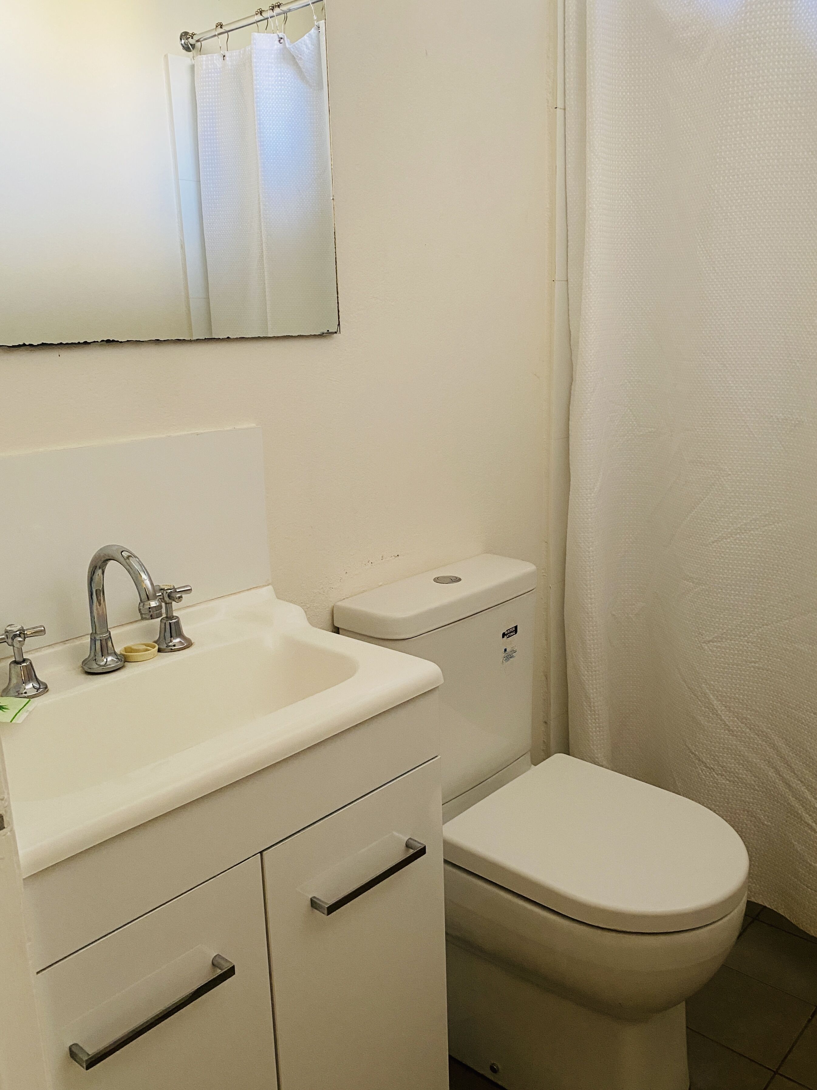 A small, clean bathroom with a white sink, a toilet, and a shower curtain.