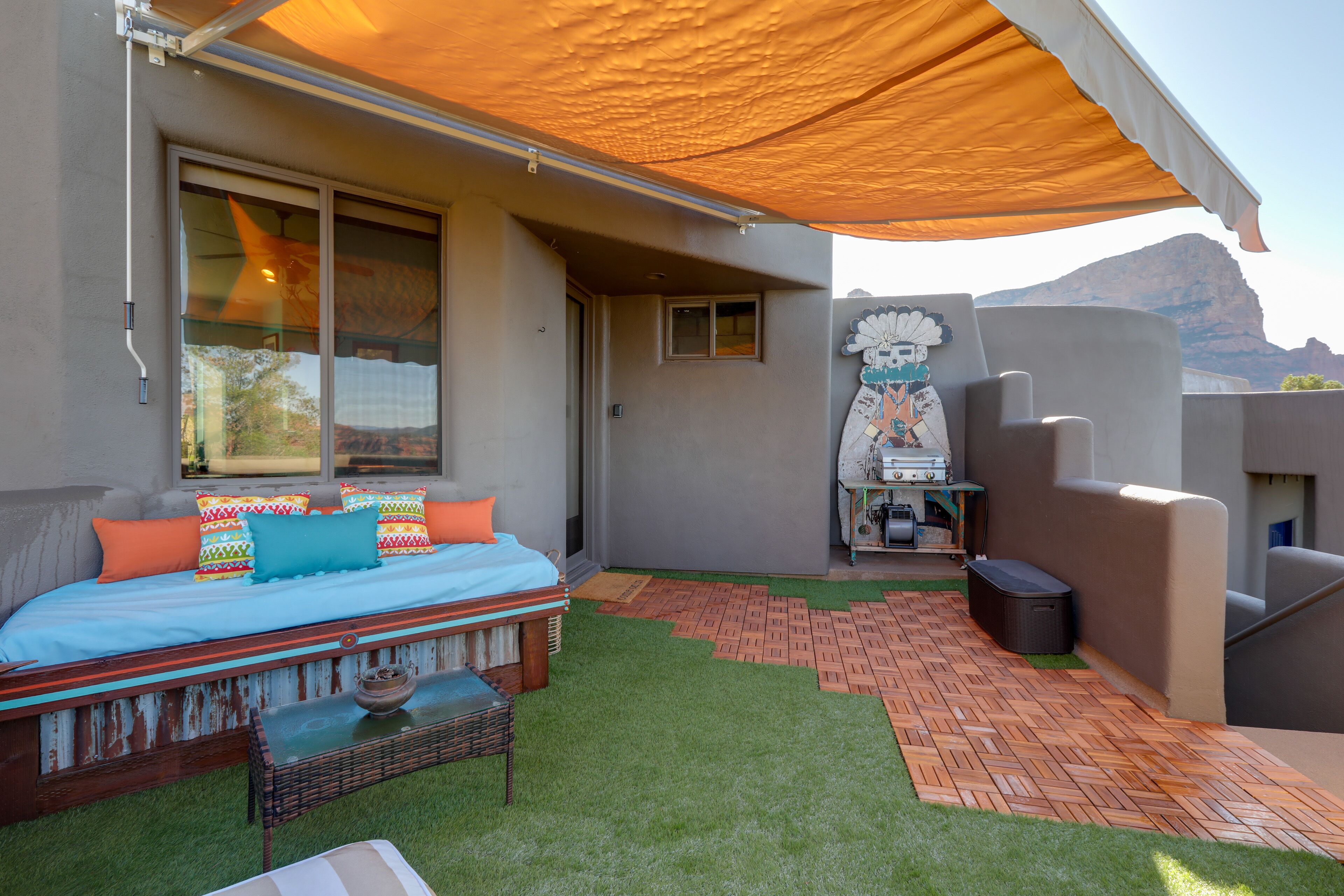 A modern outdoor living area with a bed, seating, and a barbecue setup.