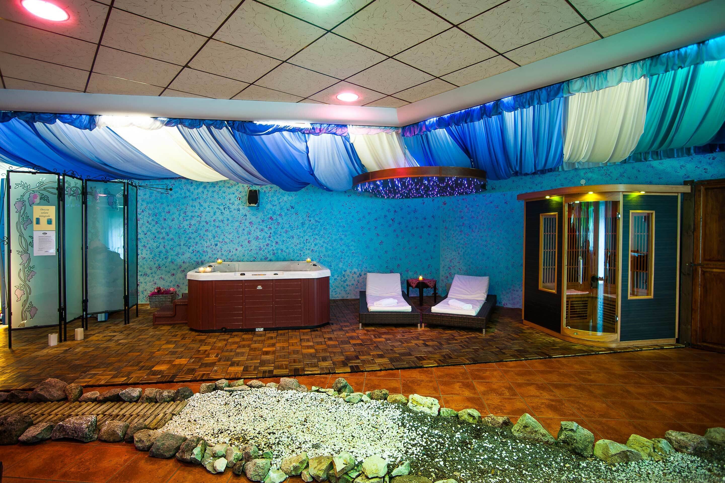 Um espaço de spa com hidromassagem, duas poltronas de descanso e uma mesa para massagem.
