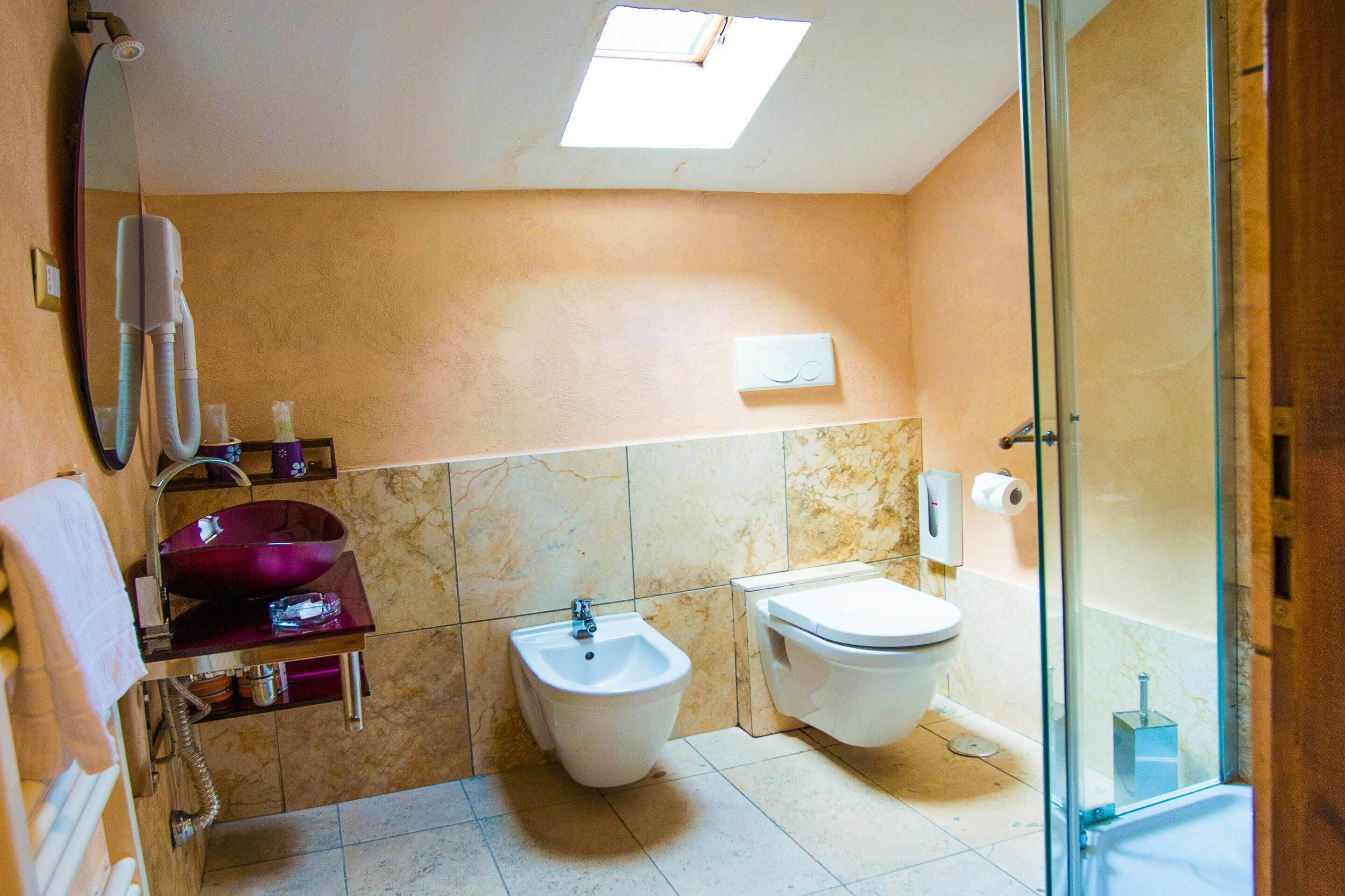 A bathroom with a bidet, toilet, and a glass-enclosed shower.