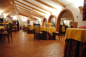 Un restaurante con vigas de madera, suelos de baldosas y mesas cubiertas con manteles amarillos.