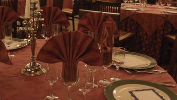 A restaurant with tables set for dining, featuring green plates and red tablecloths.