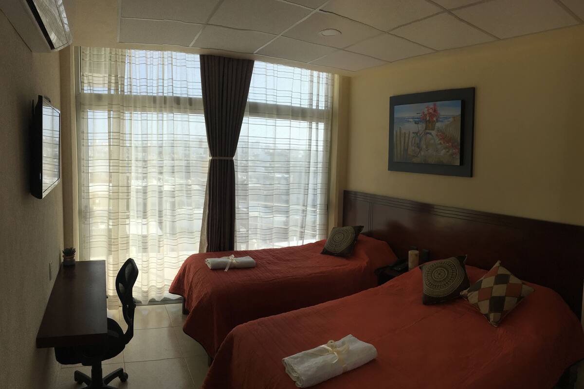 A hotel room with two beds, a desk, and a chair.