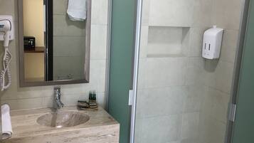 A bathroom with a sink, mirror, and shower.