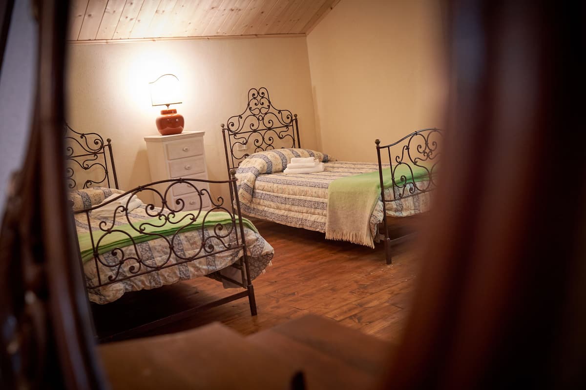 A bedroom with two metal-framed beds, a nightstand, and a lamp.