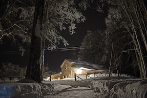 Paisaje nevado con una cabaña de madera y una valla.