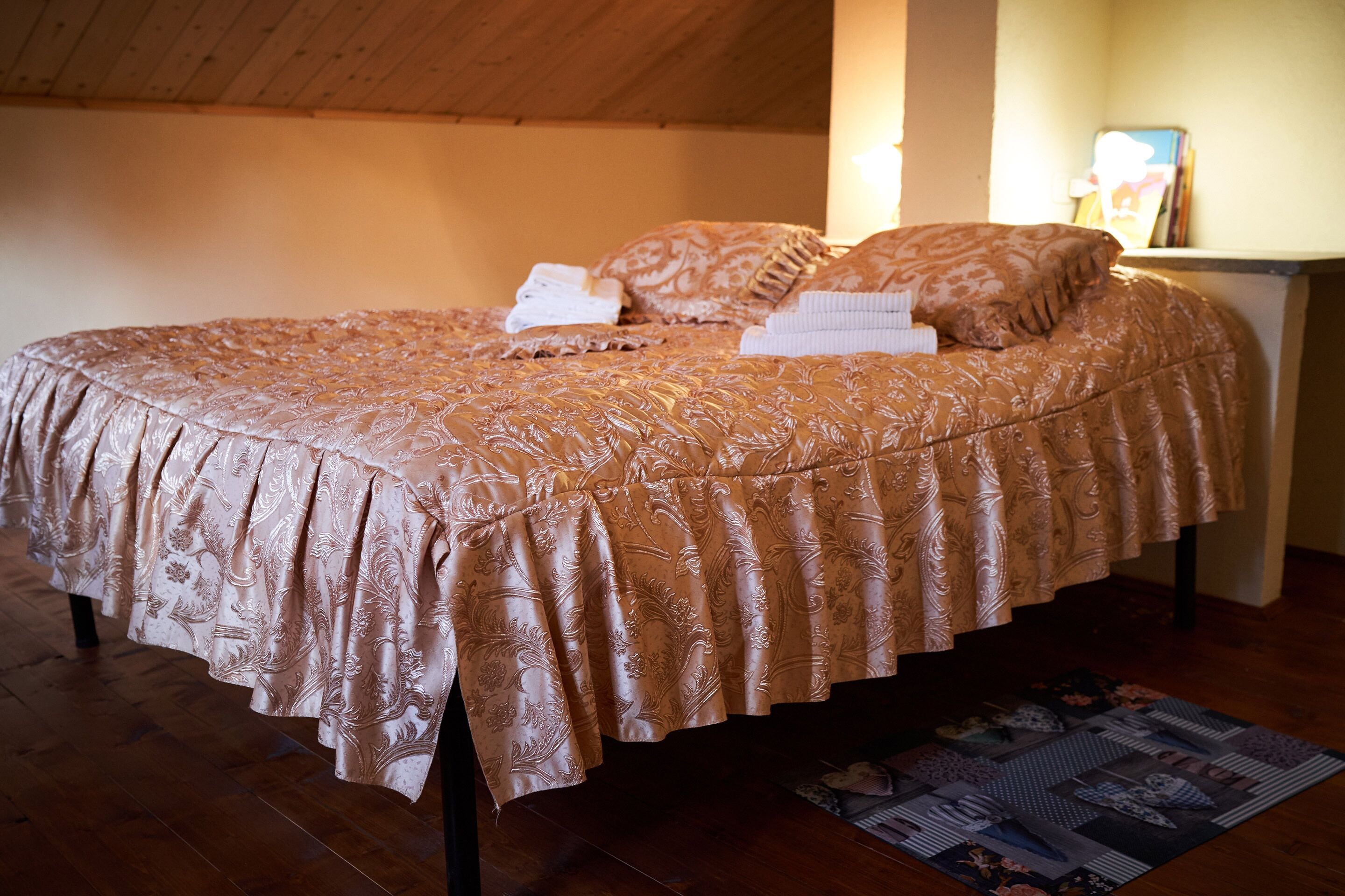 A bed with a patterned bedspread, pillows, and a folded towel.