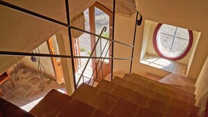 A staircase with a view of a courtyard and a window with a circular design.
