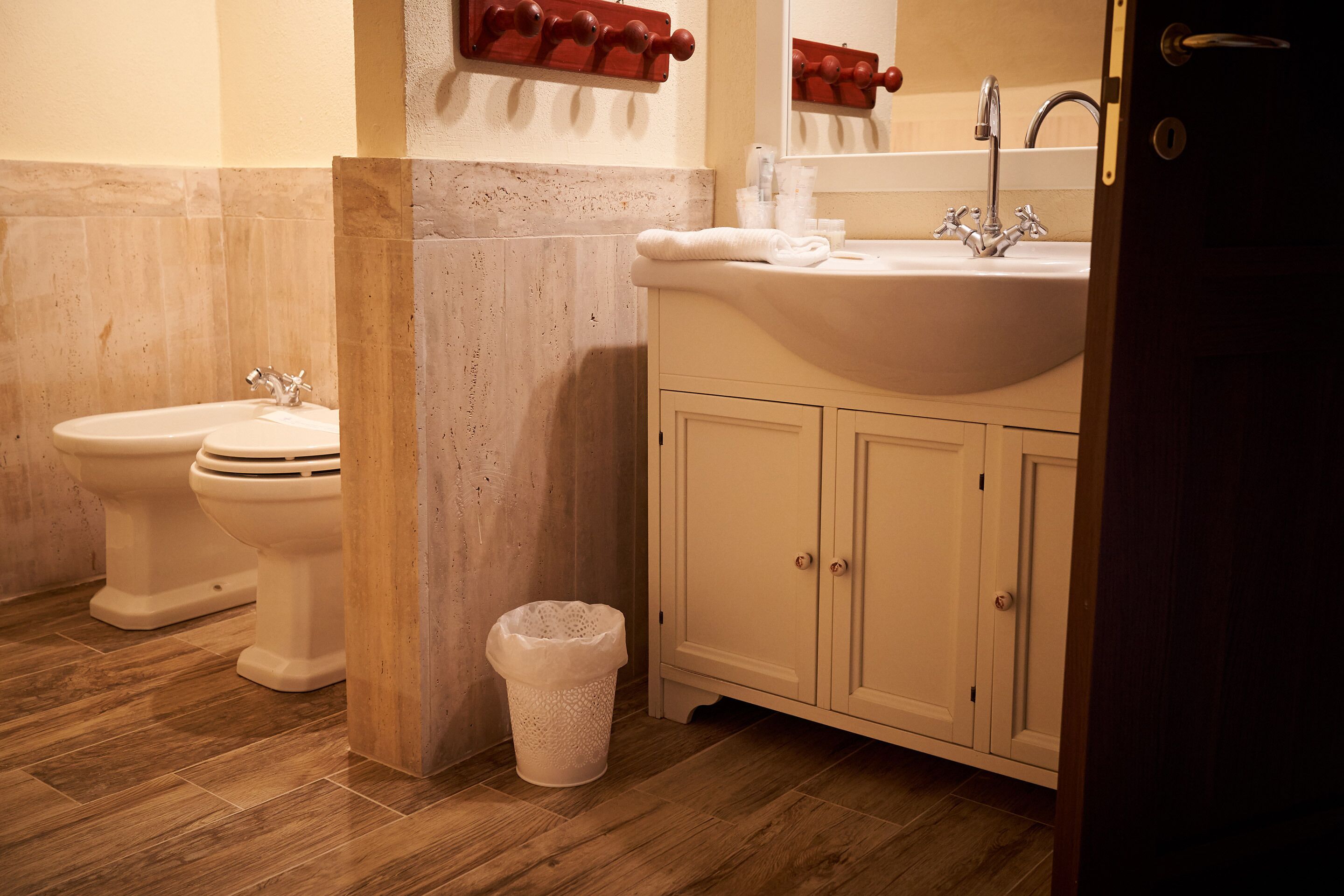 Un baño con dos inodoros, un lavabo y un cubo de basura.