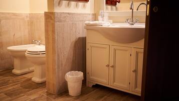 Un baño con dos inodoros, un lavabo y un cubo de basura.