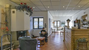 A cozy interior with a fireplace, seating area, and a kitchen visible in the background.