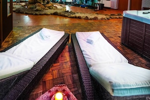 Dos camillas de masaje con toallas, un jacuzzi y un jardín de piedras al fondo.
