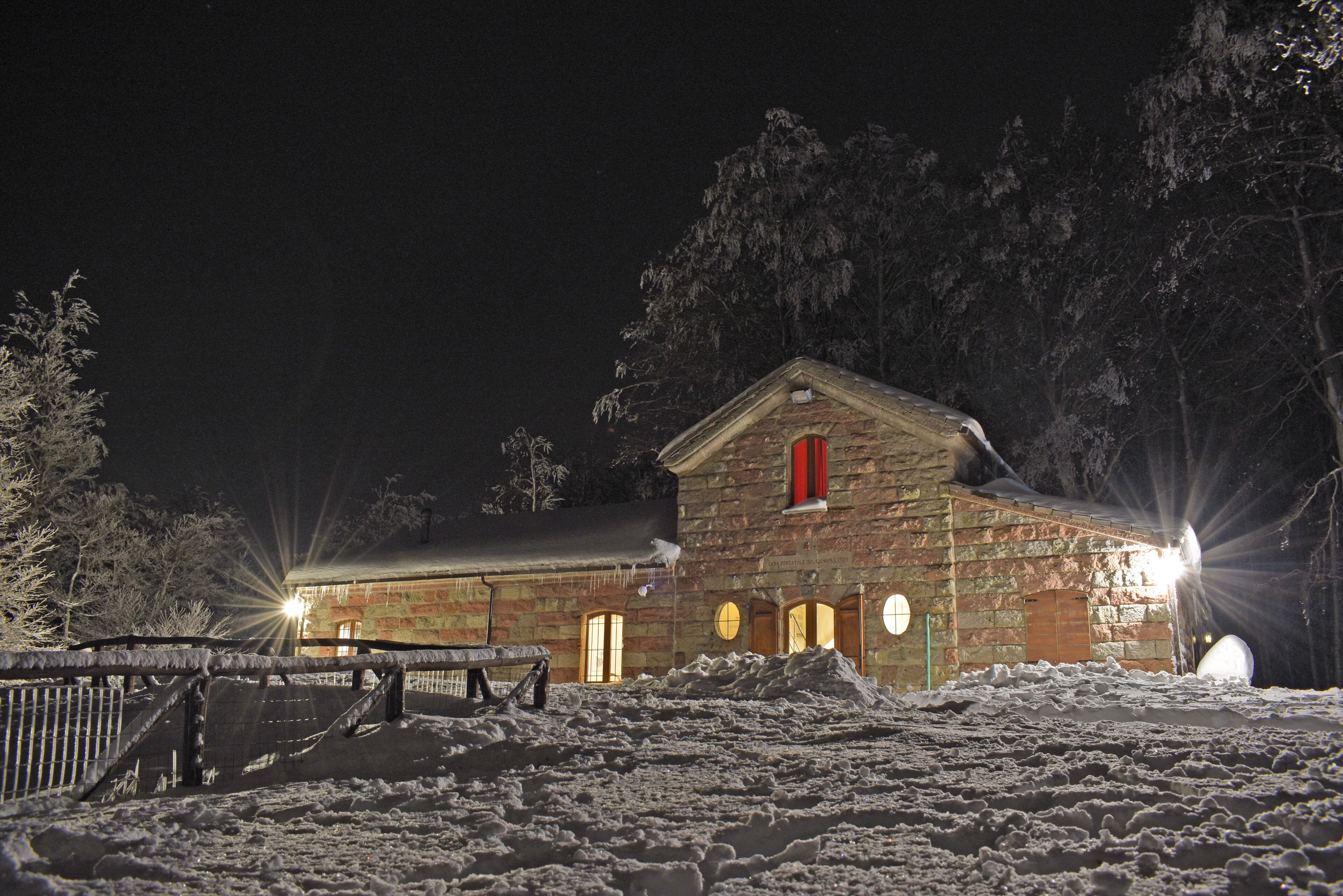 A stone building with a red window and a snow-covered ground.