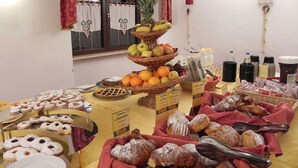 A buffet table with various food items including pastries, fruits, and condiments.