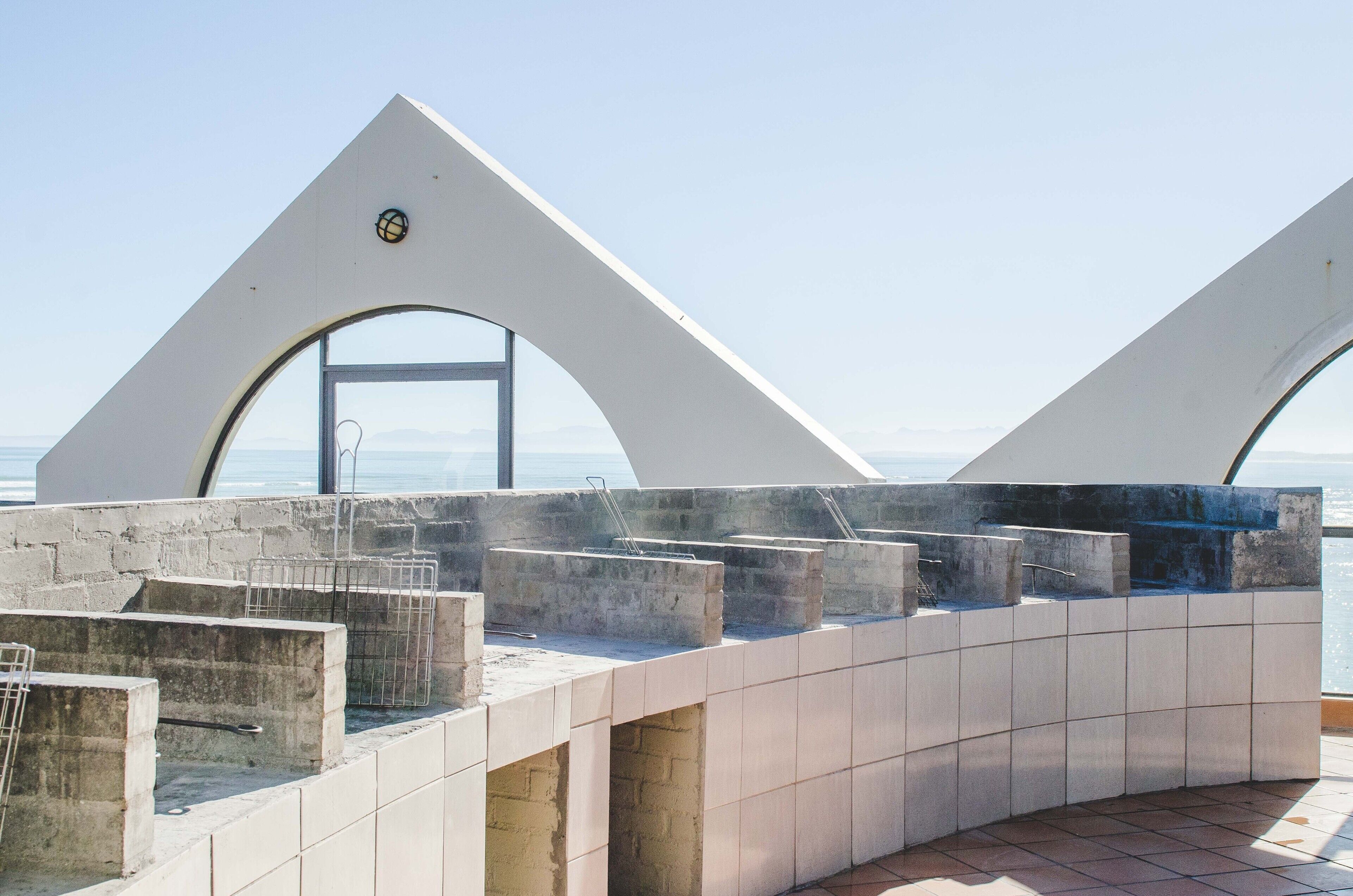 A modern architectural structure with geometric shapes and a view of the sea.