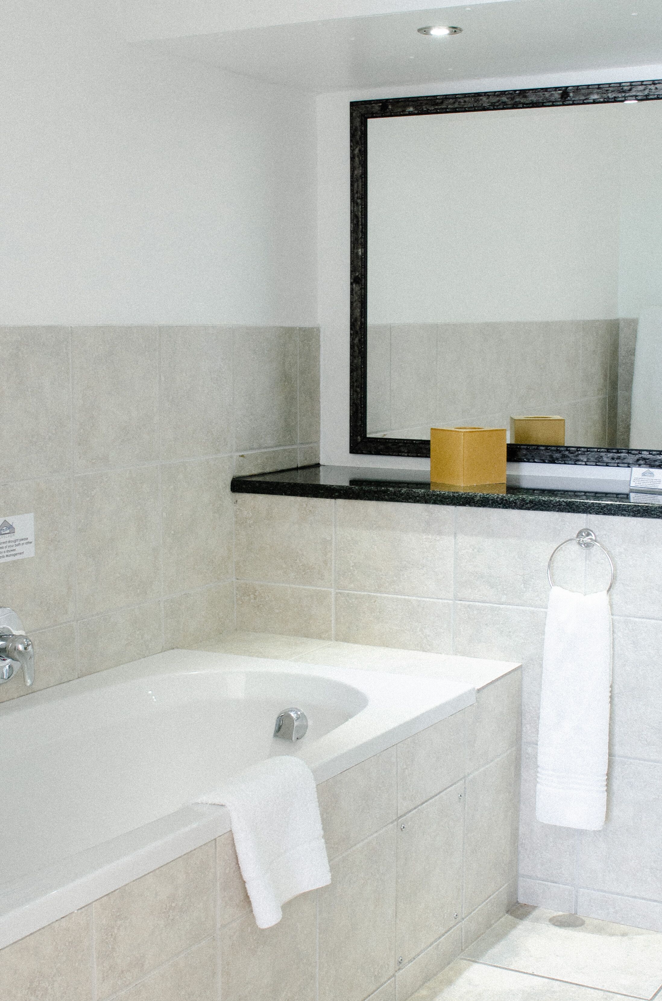 A bathroom with a bathtub, a sink, a mirror, and a towel rack.