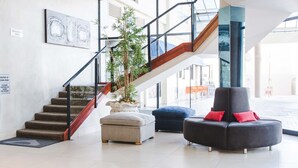 A modern lobby with a staircase, a potted plant, a seating area, and a 'Resident's Only' sign.