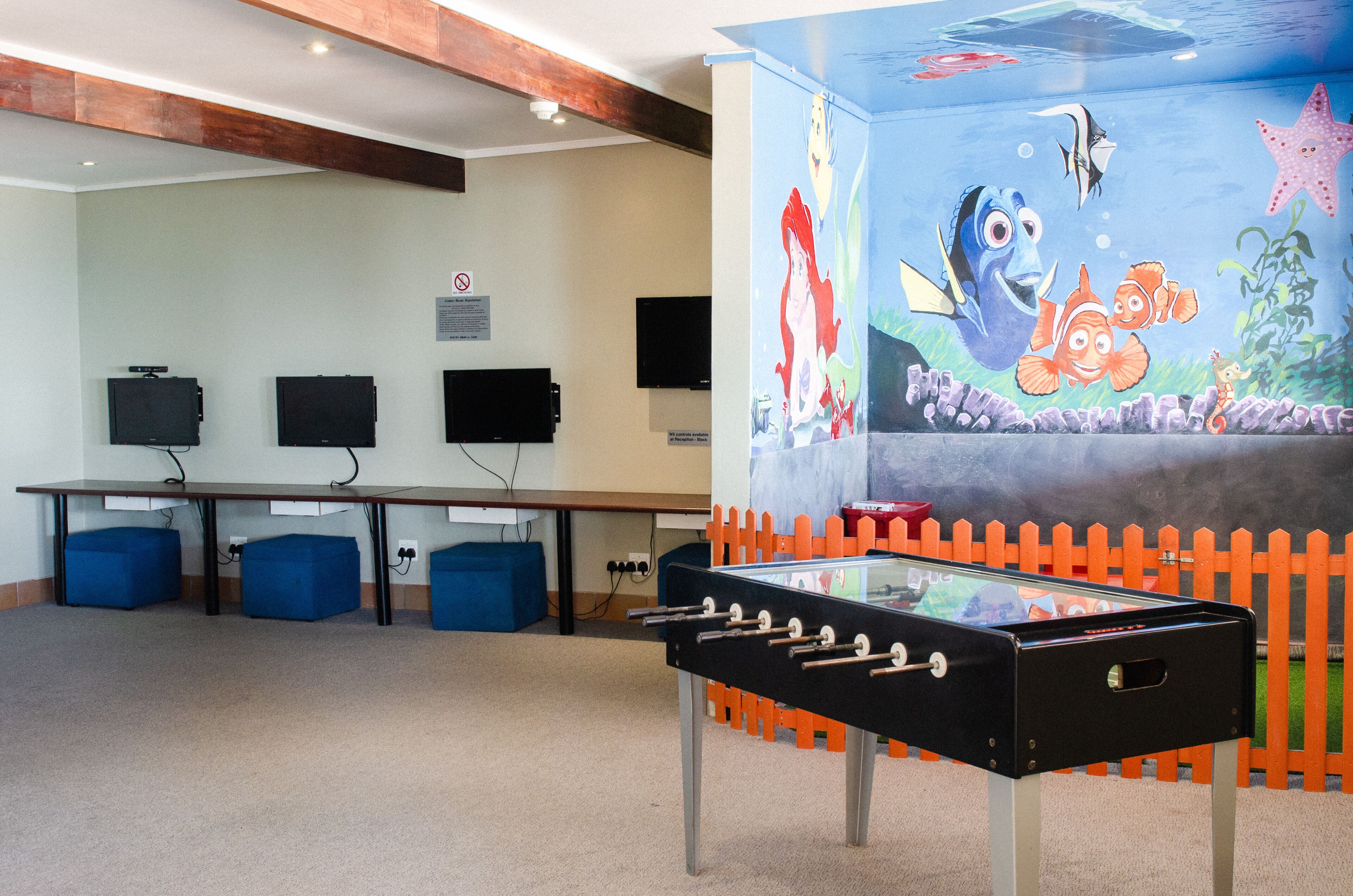 Une pièce équipée d’un baby-foot, d’une télévision et ornée d’une fresque représentant des personnages sous-marins.