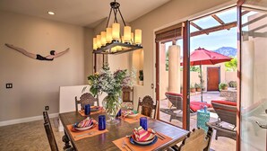 A dining area with a wooden table set for four, a chandelier, and a view of the outdoors through a glass door. - 222396 3BR Escape w/ Fire Pit: 1 Mi to Old Town (La Quinta)