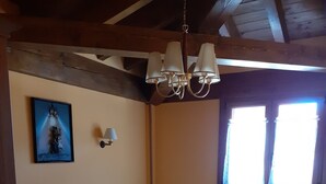 Una habitación con dos camas, techo de madera, un radiador y una ventana con cortinas.