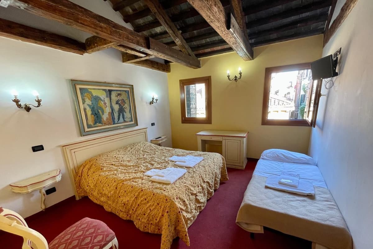 A bedroom with a bed, a desk, a chair, and a window.