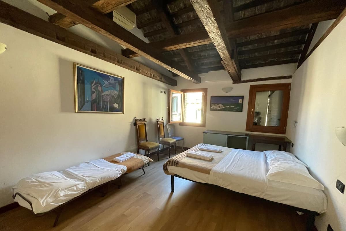 A room with two single beds, a desk, a chair, and a window.